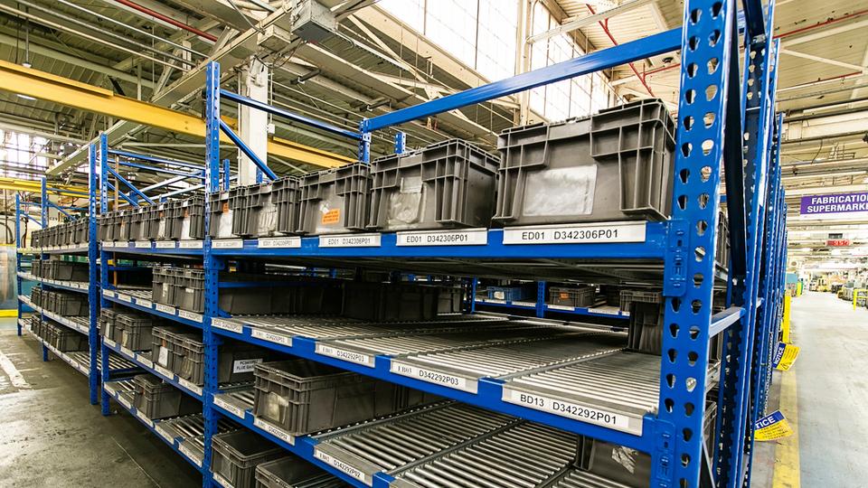 Modular industrial workstation with flow racks with storage bins.